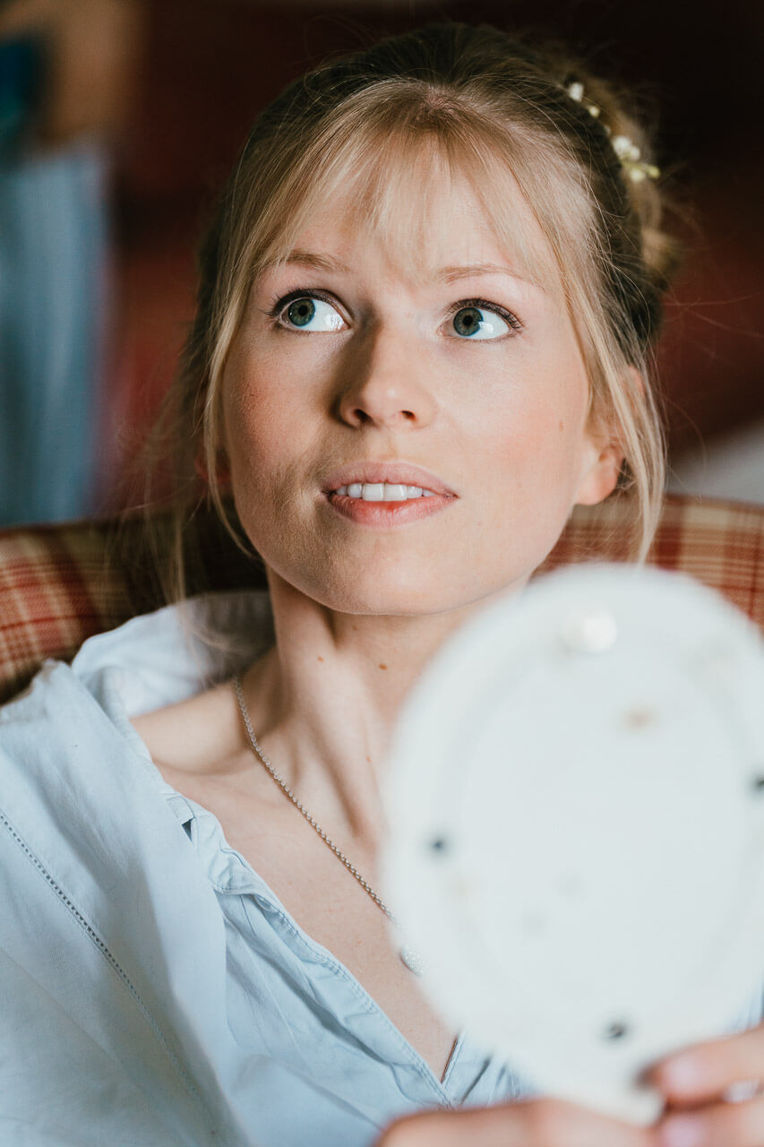 close up of bride holding mirror having make up done