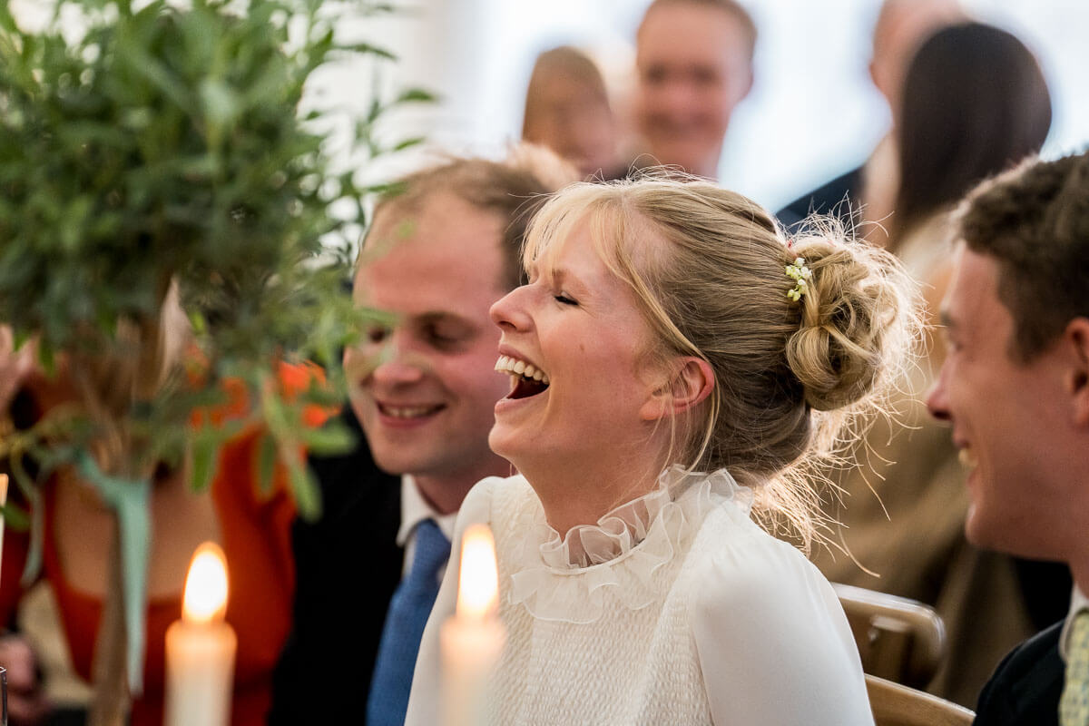 bride laughing at speech during wedding
