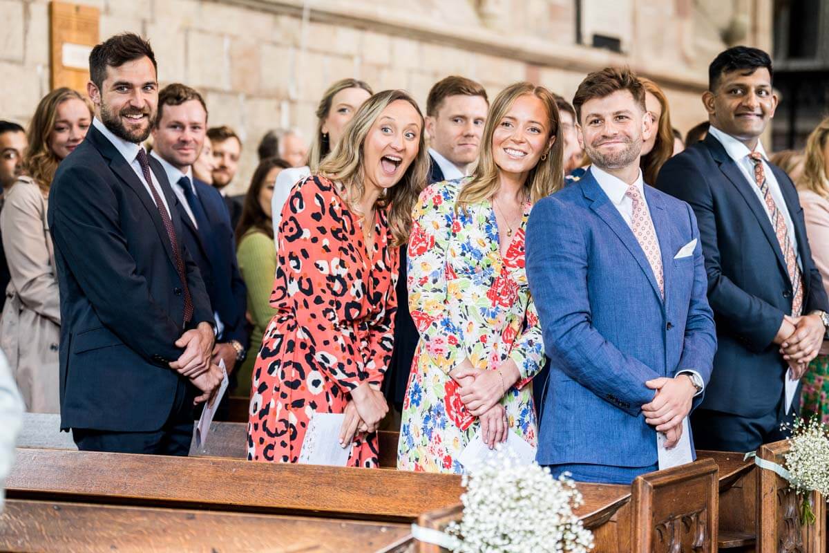 guests reactions of smiles in church as the bride walks in

