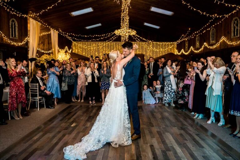 couple doing first dance with guests all standing behind them