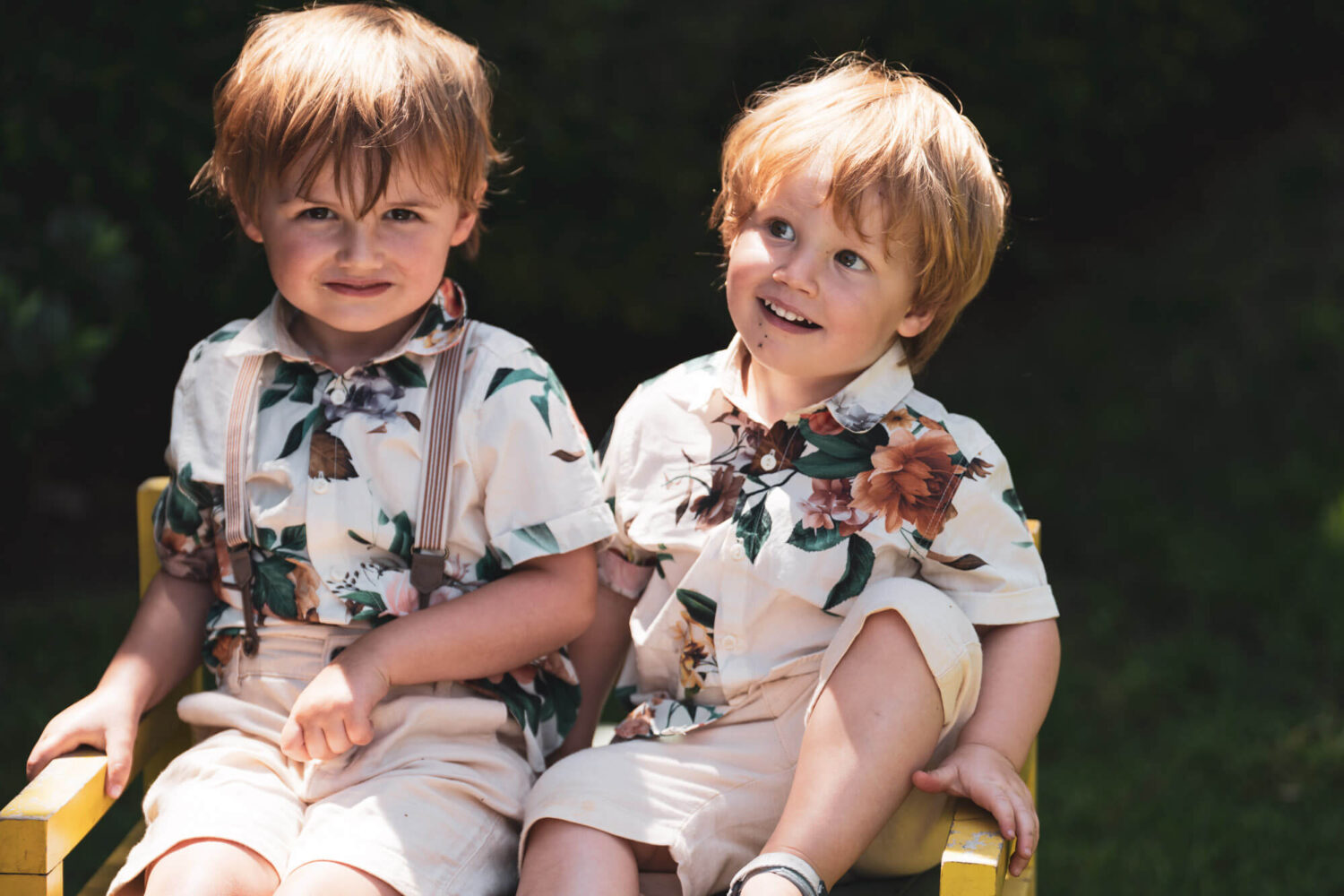 two kids sitting in same chair looking cheeky