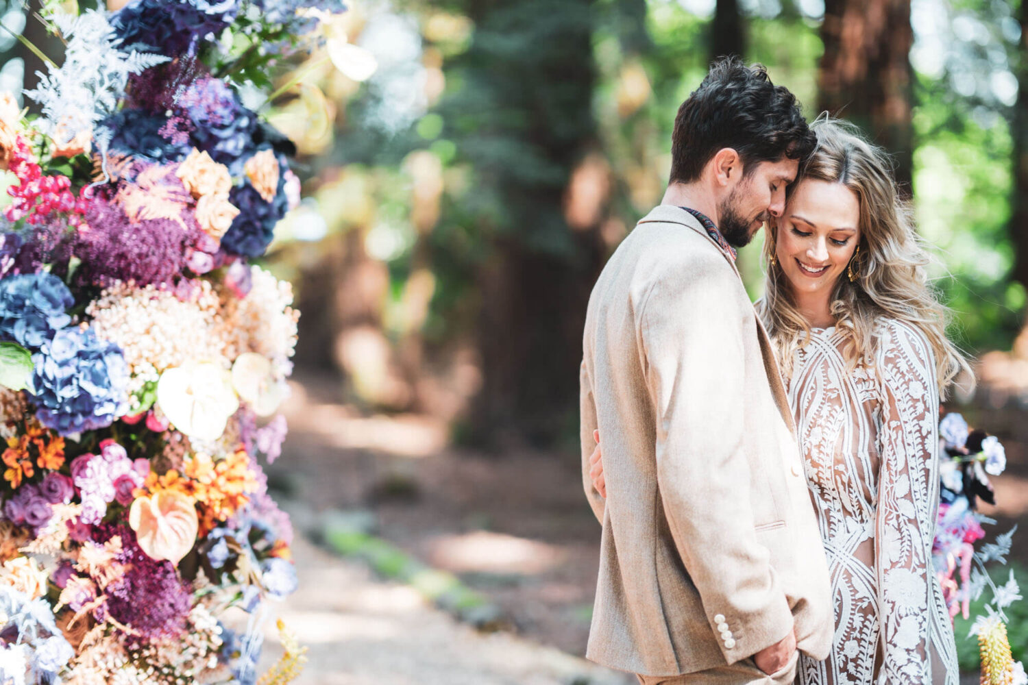 with flowers in corner, groom leaning head into woman's head both looking down