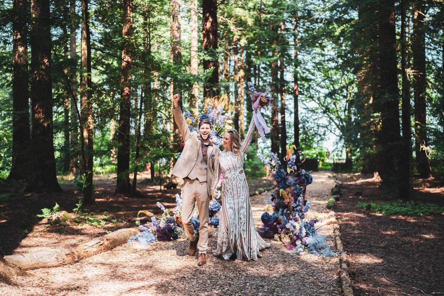 bride and groom walking towards camera with arm up in the air with happiness