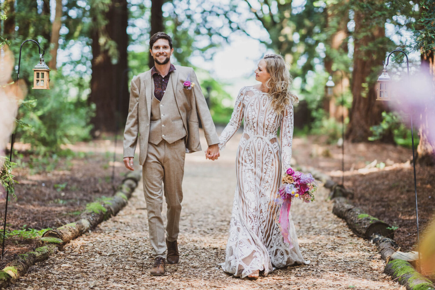 bride looking at groom walking along pathway in stunning redwood forest