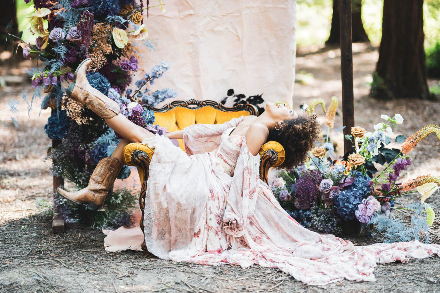 woman in cowboy boots and awesome flowing dress sitting in chair with head tilted back laughing