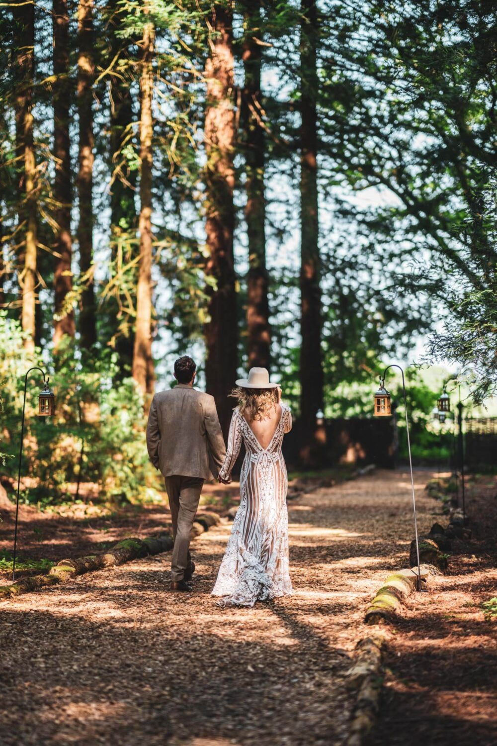 bride and groom portrait walking away from camera in stunning redwood forest dappled light
