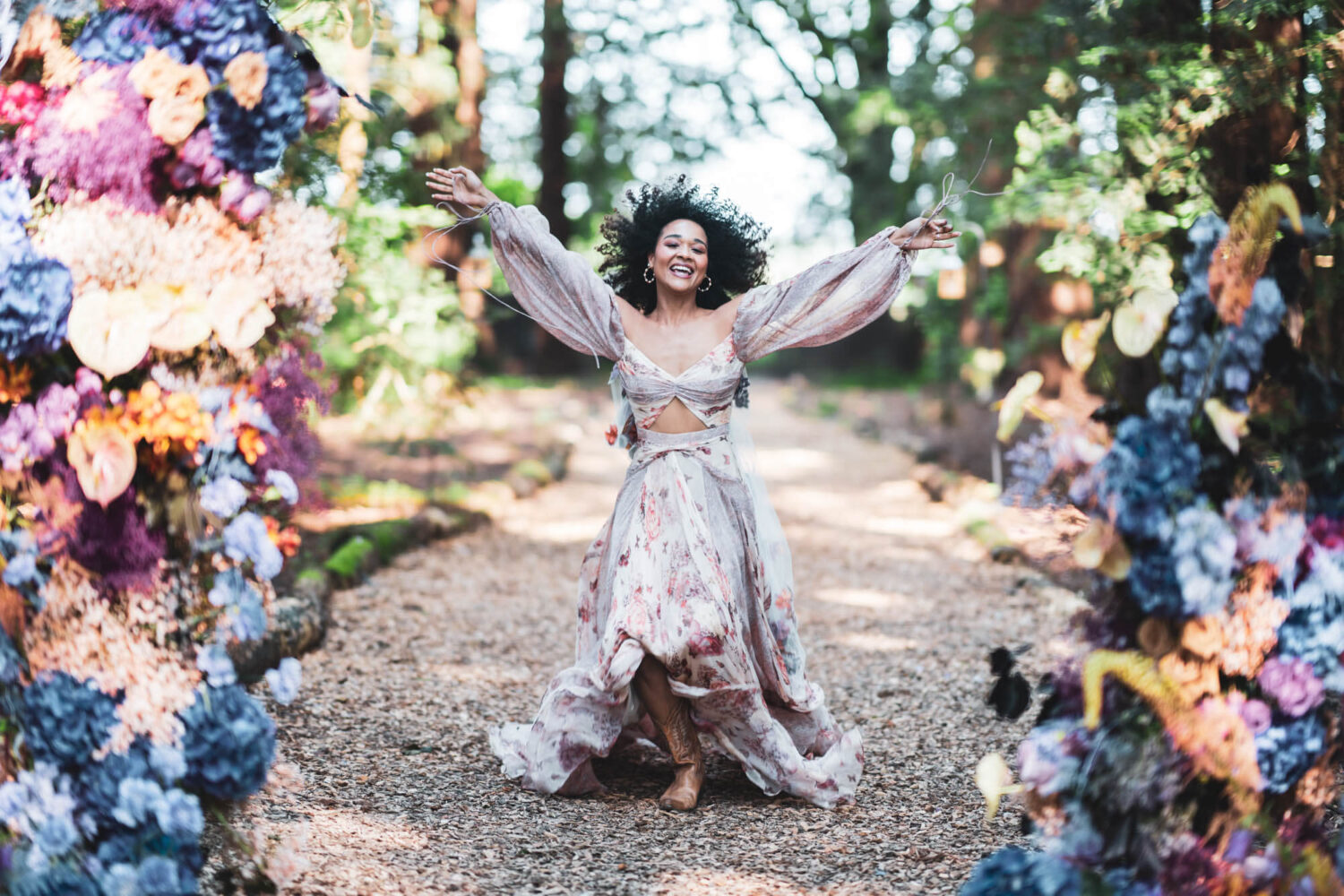 woman running towards camera with florals either side in stunning redwood forest