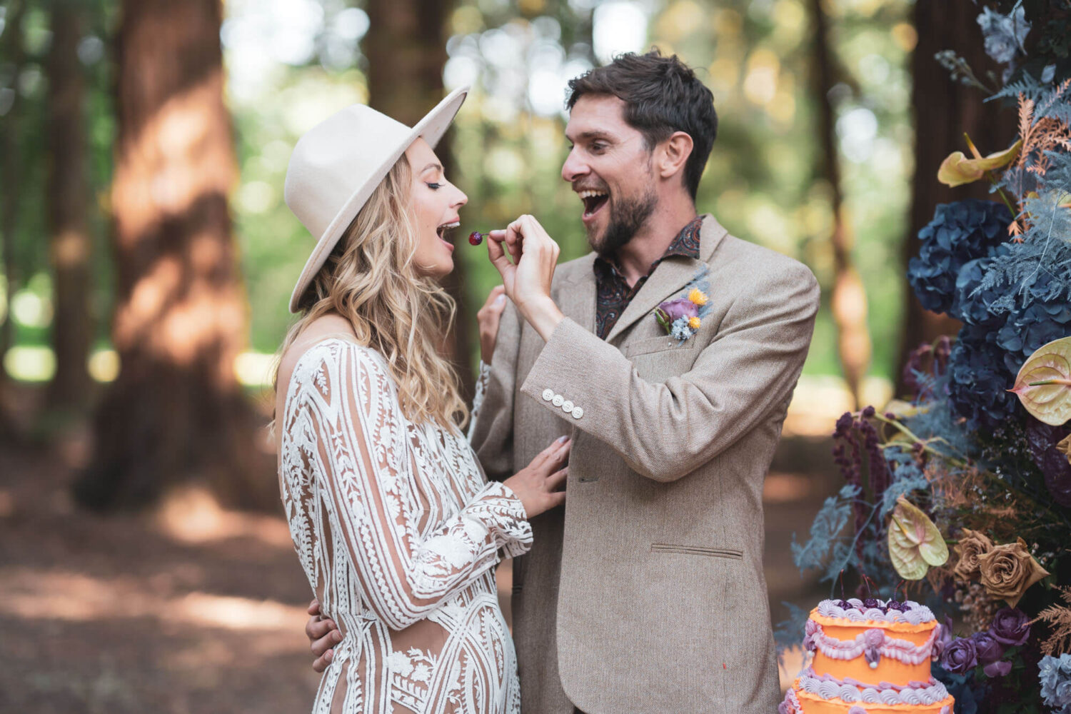 groom feeding bride cherry from the cake in redwood forest