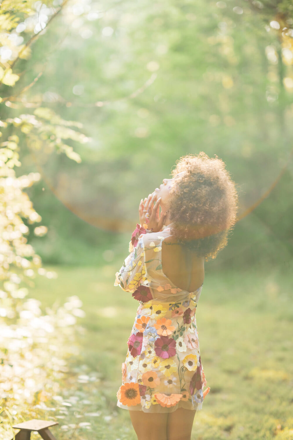 golden hour light on woman in floral dress looking away from camera
