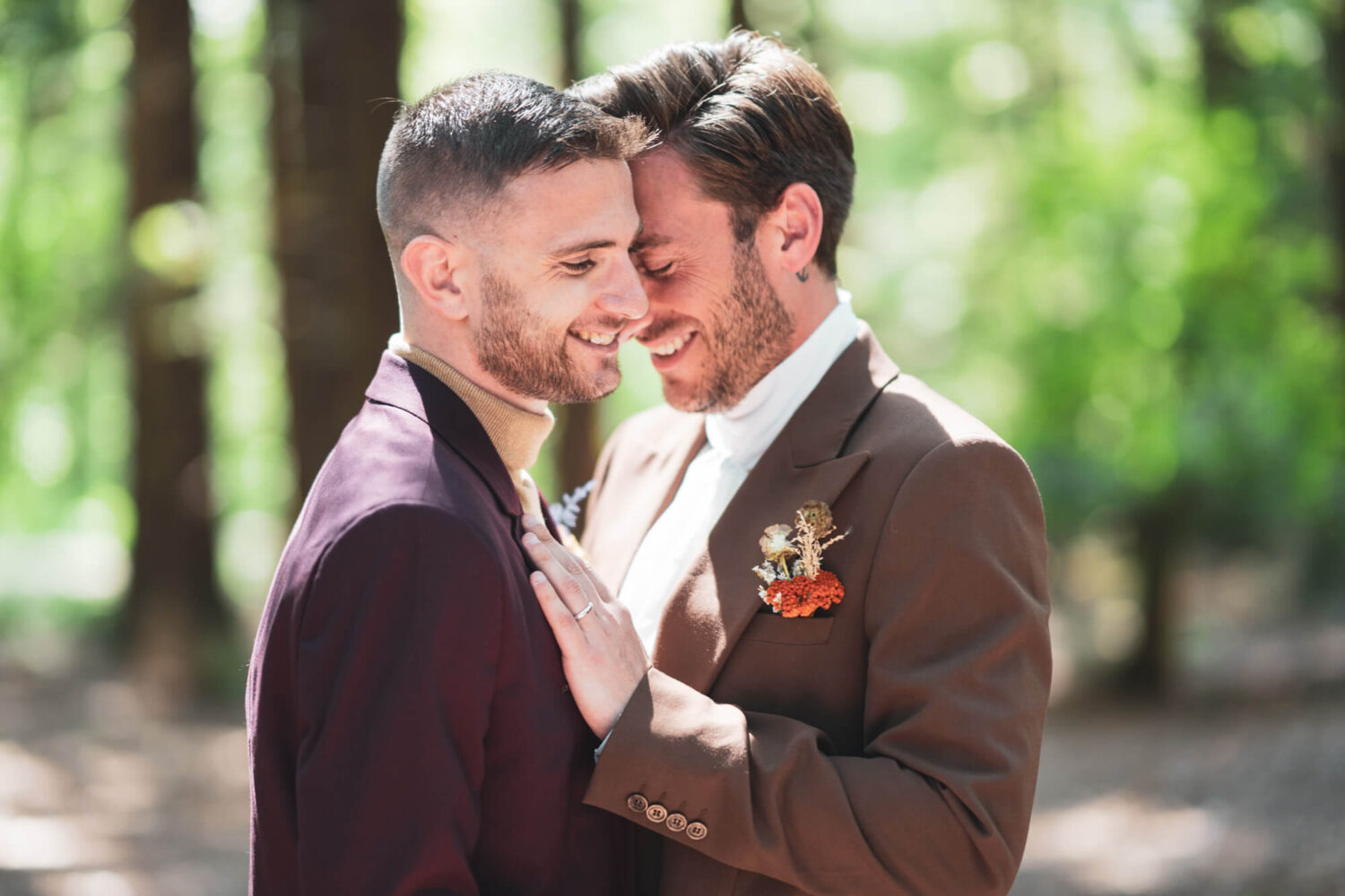 two grooms with heads together and one hand on partner's chest