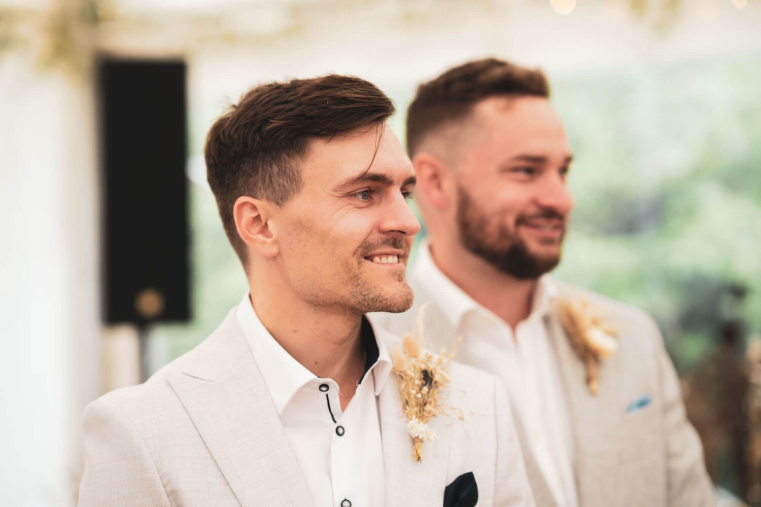 close up of groom smiling as he watches bride arrive