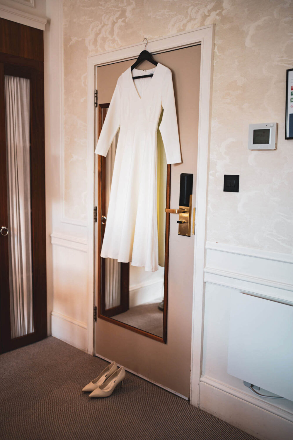 wedding dress and wedding shoes hanging on back of door