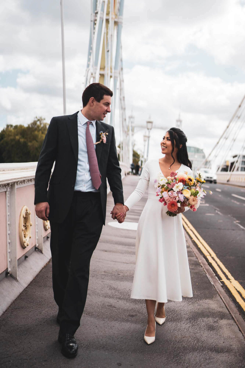 couple walking along Albert bridge looking at each other