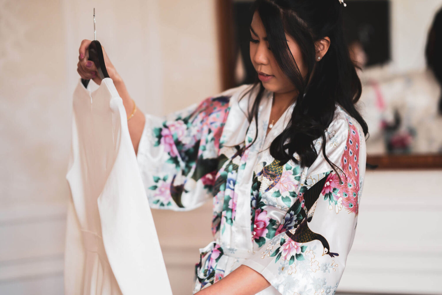 bride holding and looking at wedding dress on hanger