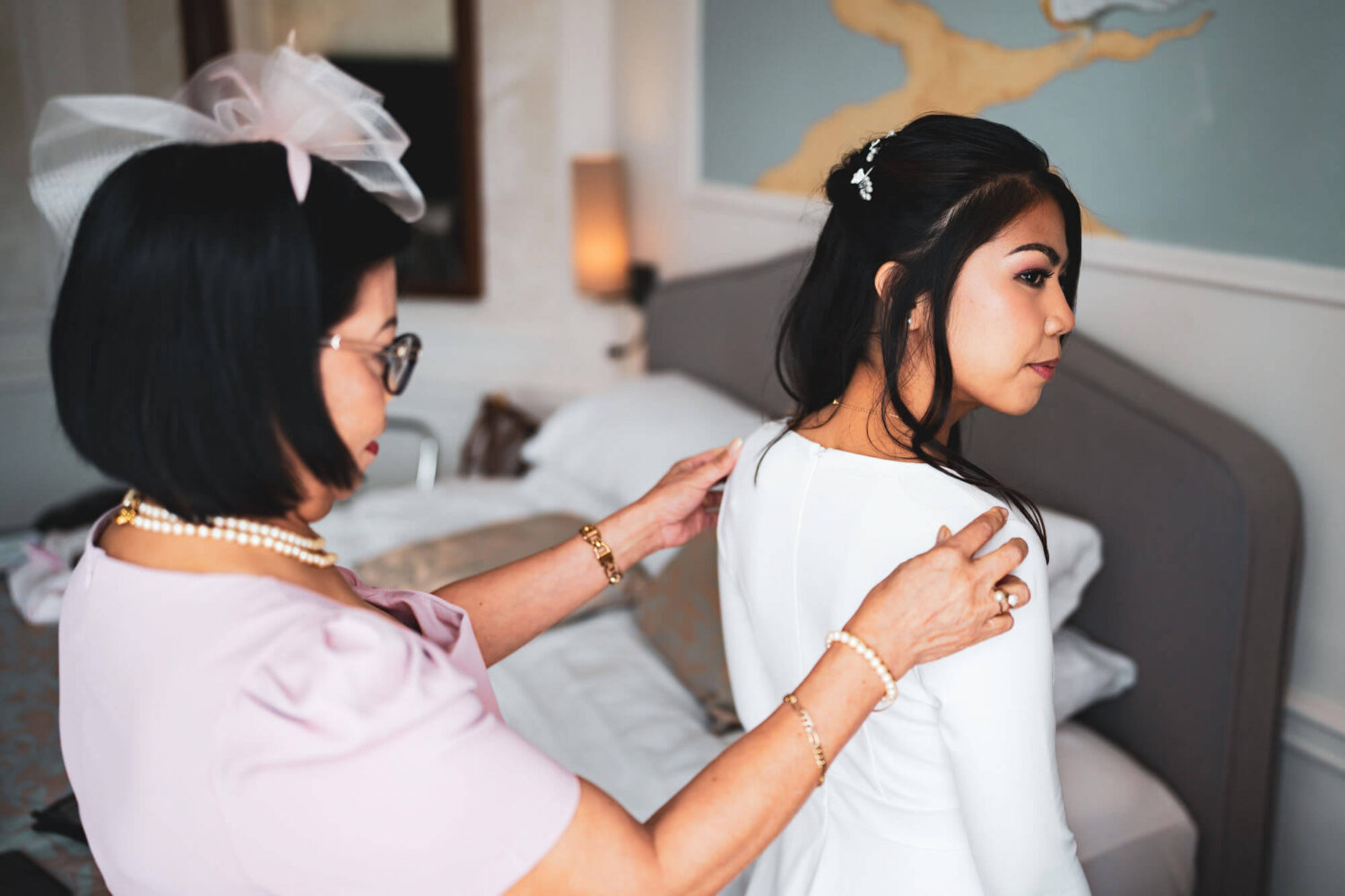 mother of the bride doing up the back of the bride's dress