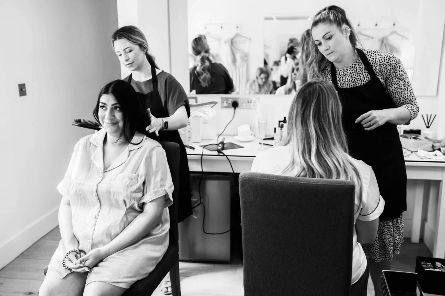 bridesmaid and bride having make up done one with back to camera one facing the camera