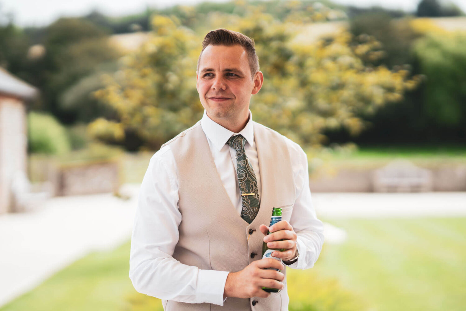 groom holding beer bottle looking away from camera