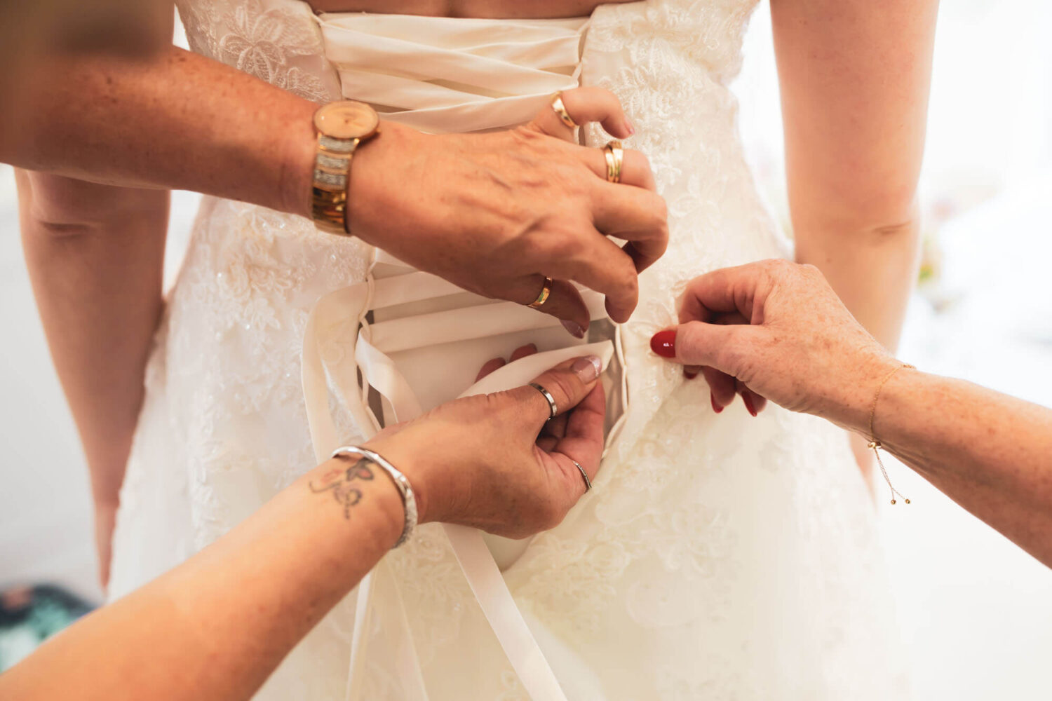 close up of dress being done up by aunt and mother