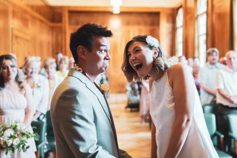 groom pulling a face and bride laughing as they say their i do's at hackney town hall