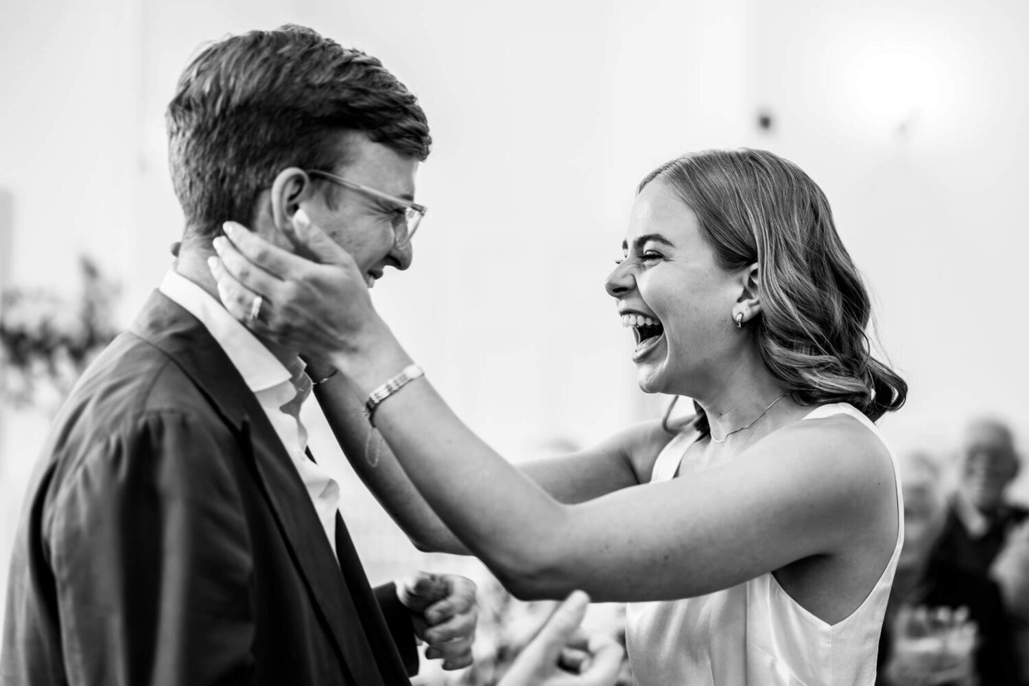 bride cupping groom's hands smiling with joy after getting married