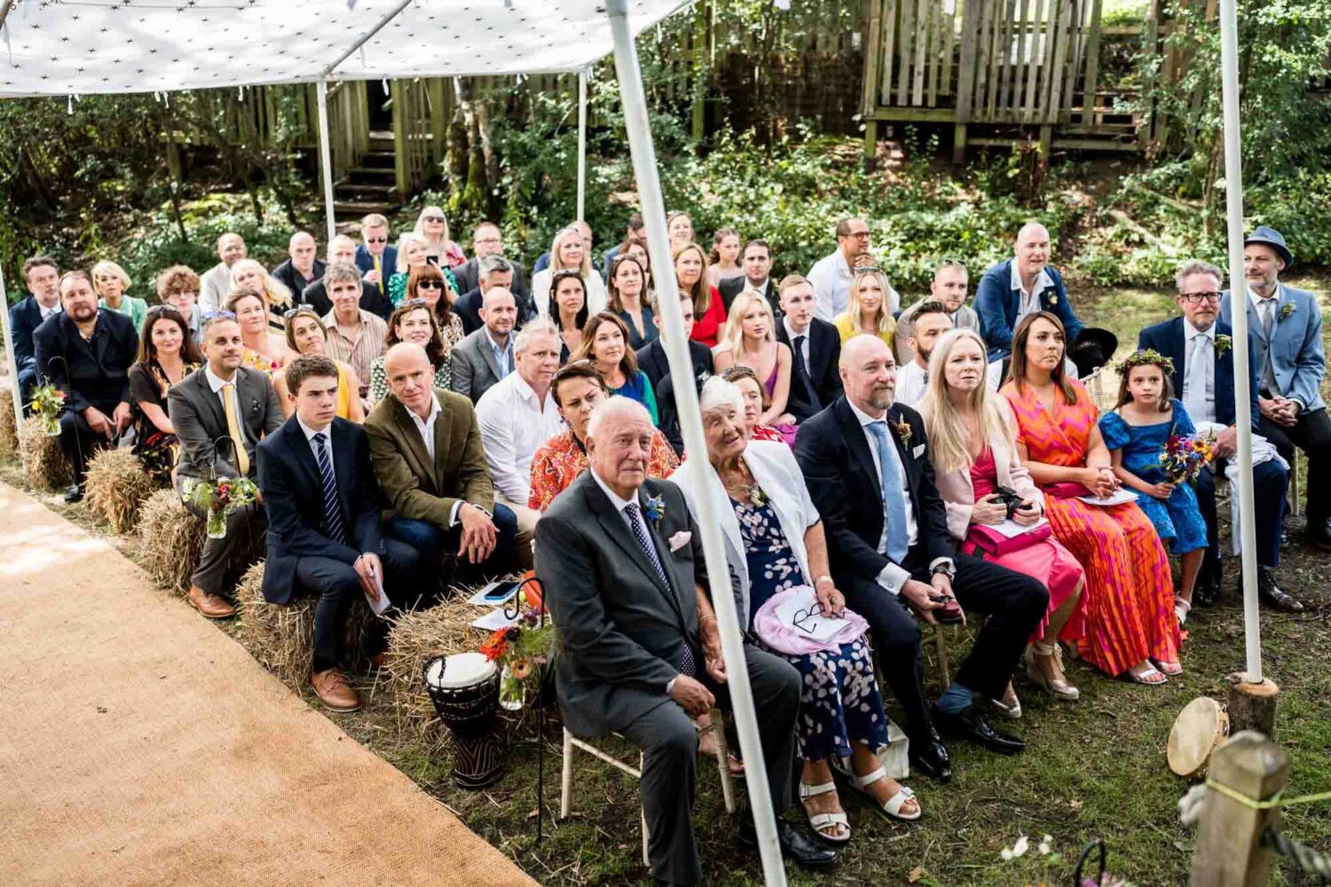 wide angle shot of wedding guests sitting on hay bales