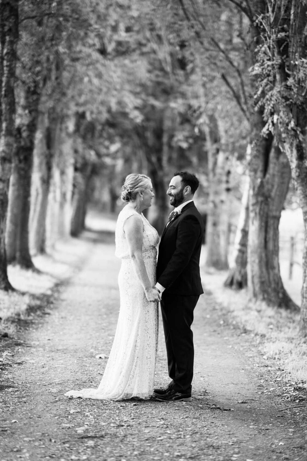 couple portrait standing in land with trees either side