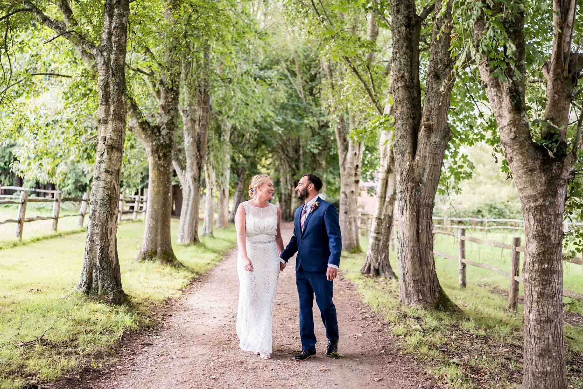 couple standing in woodland wedding venue crockstead fields holding hands looking at each other