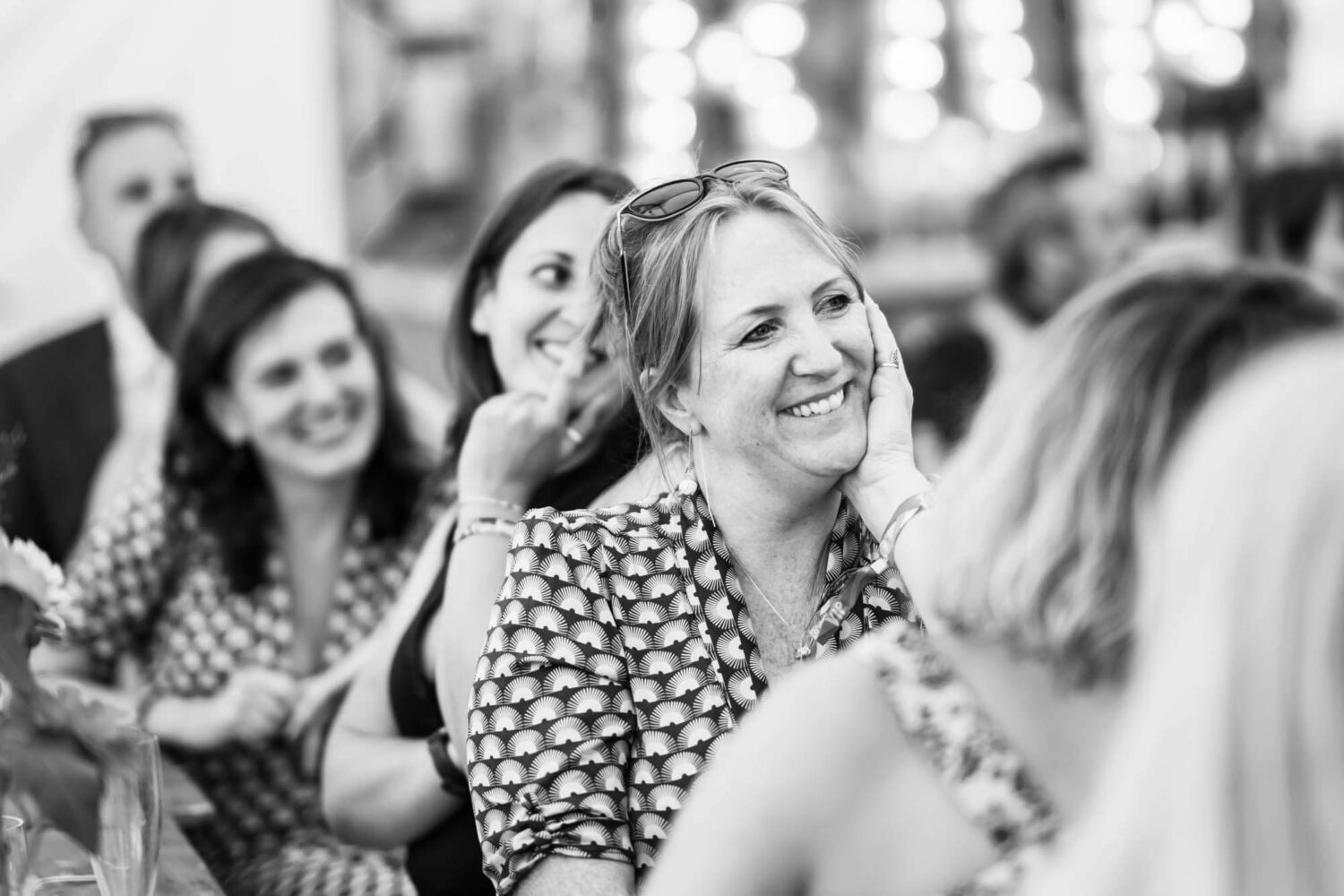 guest smiling with hand on face listening to wedding speeches