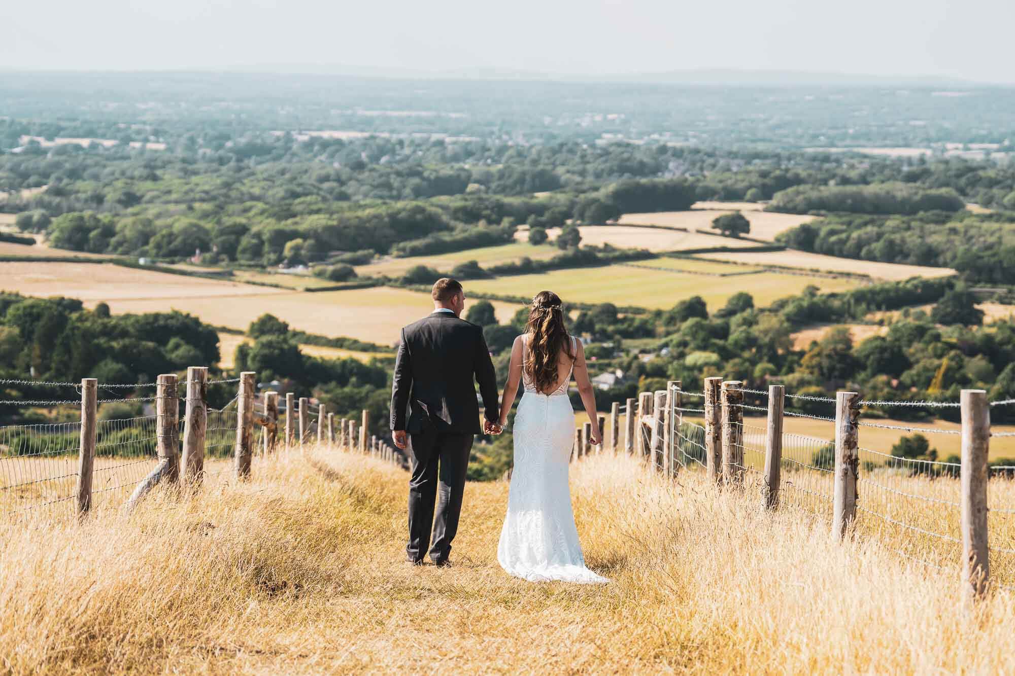 bride and groom walking away down hill on the South Downs