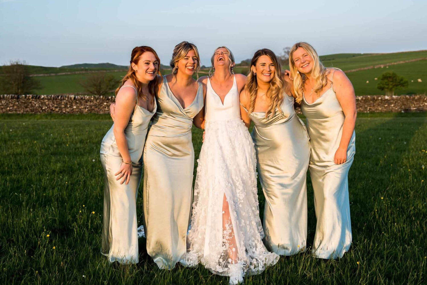 golden hour bride with bridesmaids all huddled together smiling