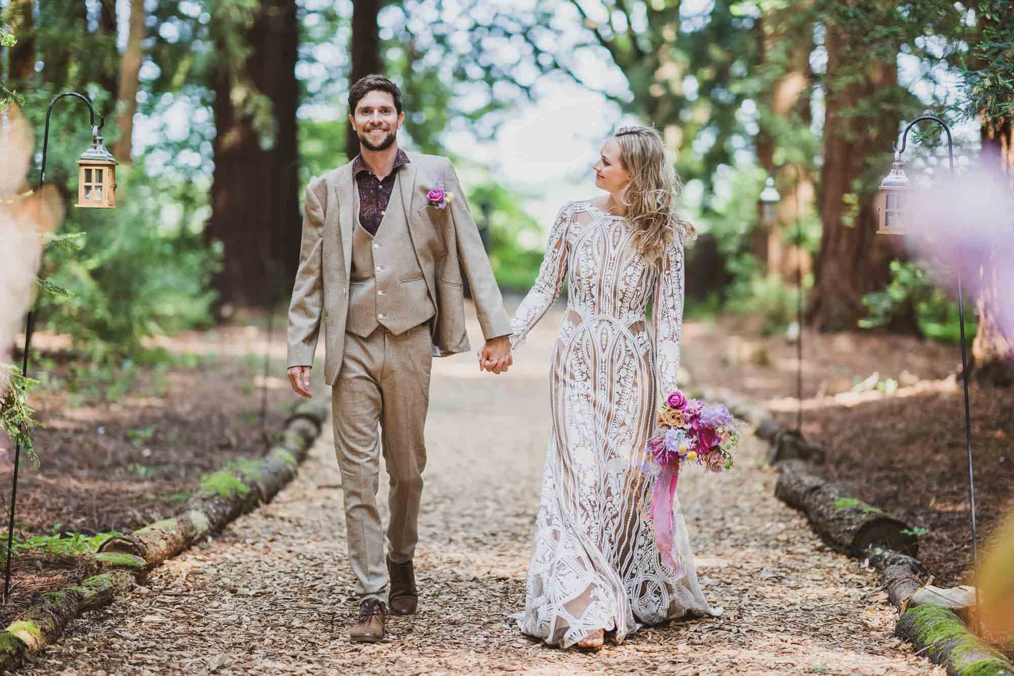 bride and groom walking through woods bride smiling at groom