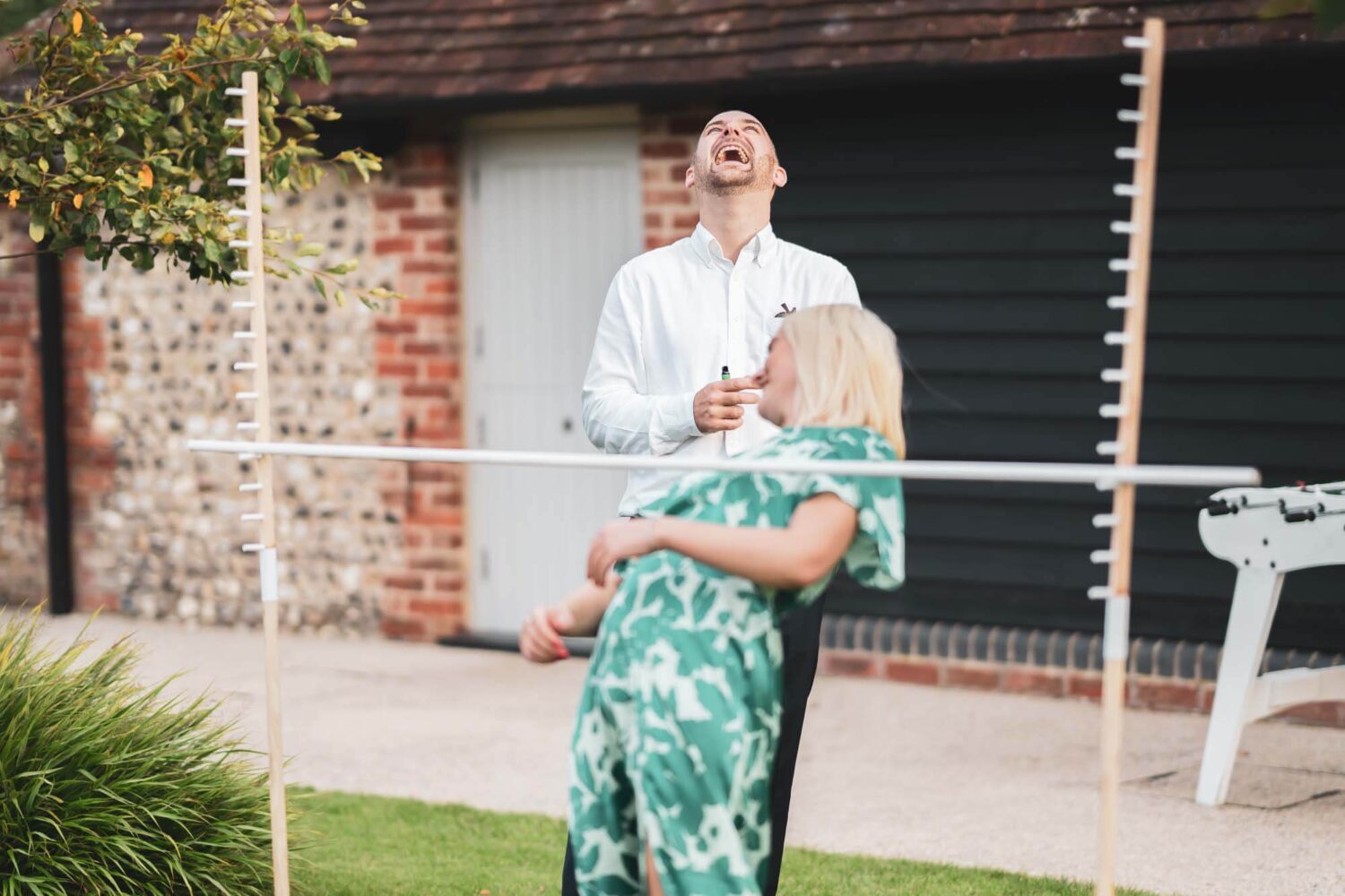 guy laughing at woman trying to lower herself under a pole
