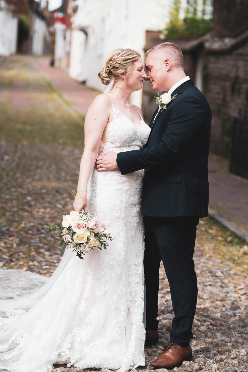bride and groom embracing each other standing on cobbled street