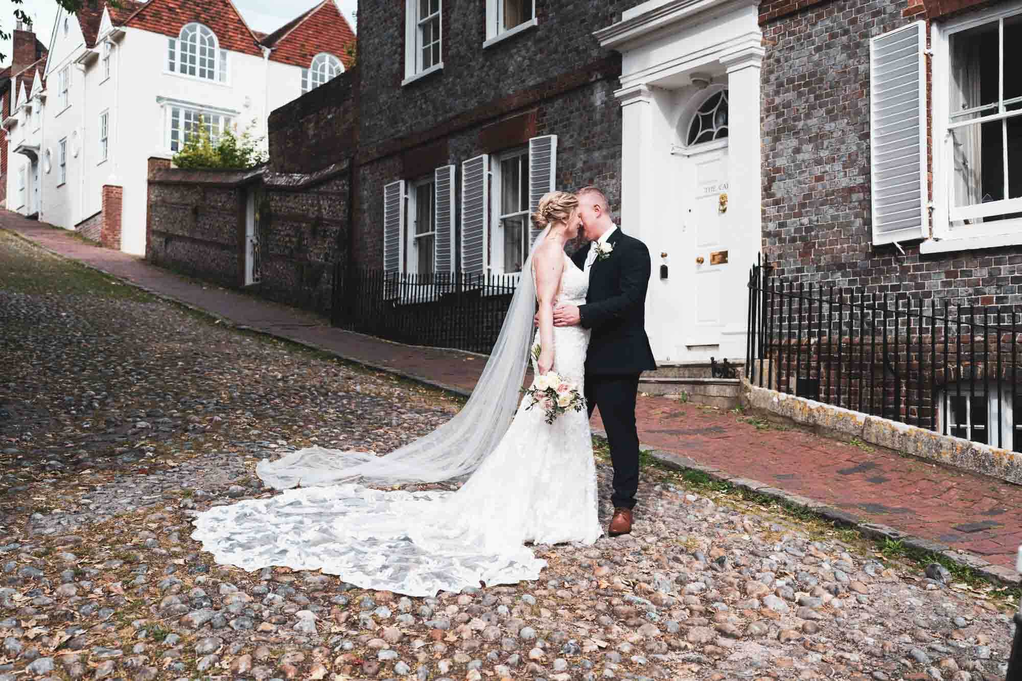 bride and groom holding each other looking into each other on cobbled street in lewes