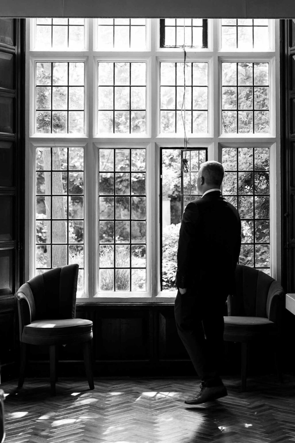 groom waits for his bride looking out of window