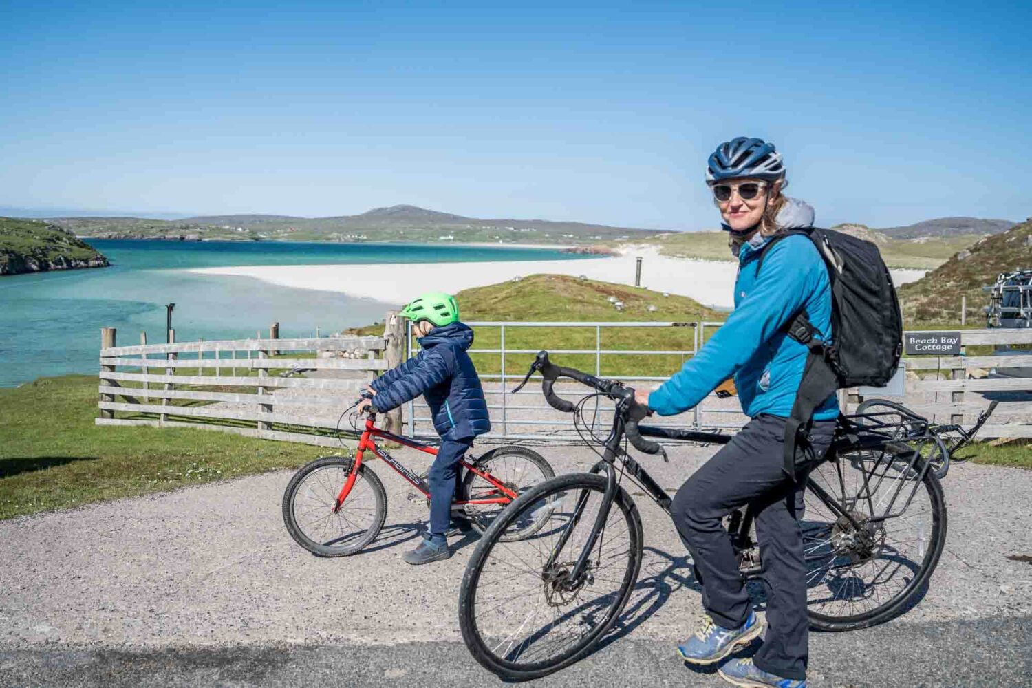 woman on bike looking at camera with boy behind on bike looking out to Uig beach bay