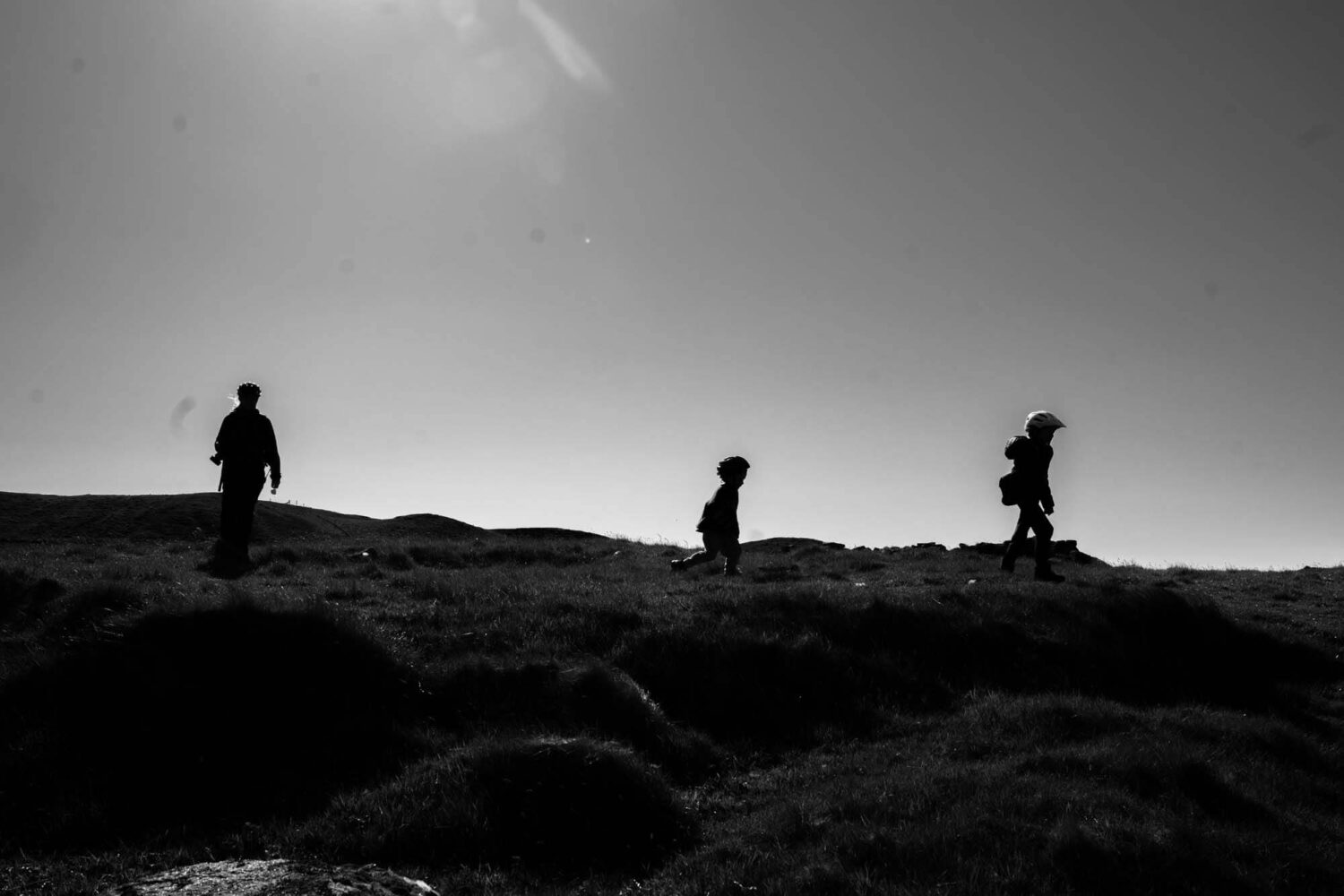 silhouette of three people on top of a hill
