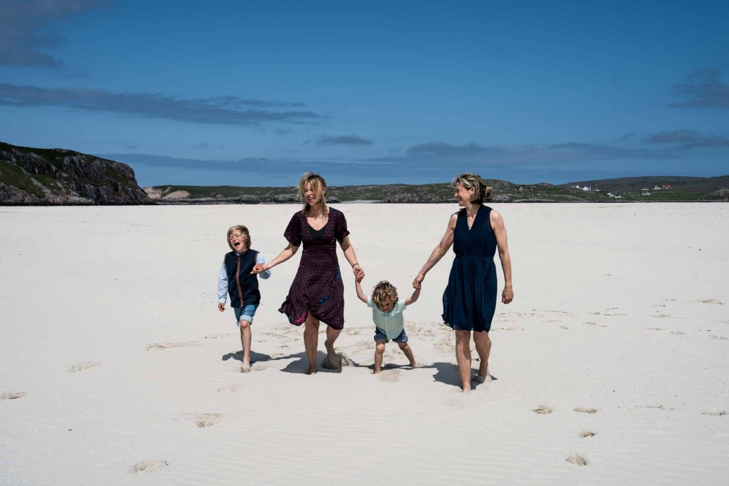 two mum family walking hand in hand with their two boys Uig beach lewis