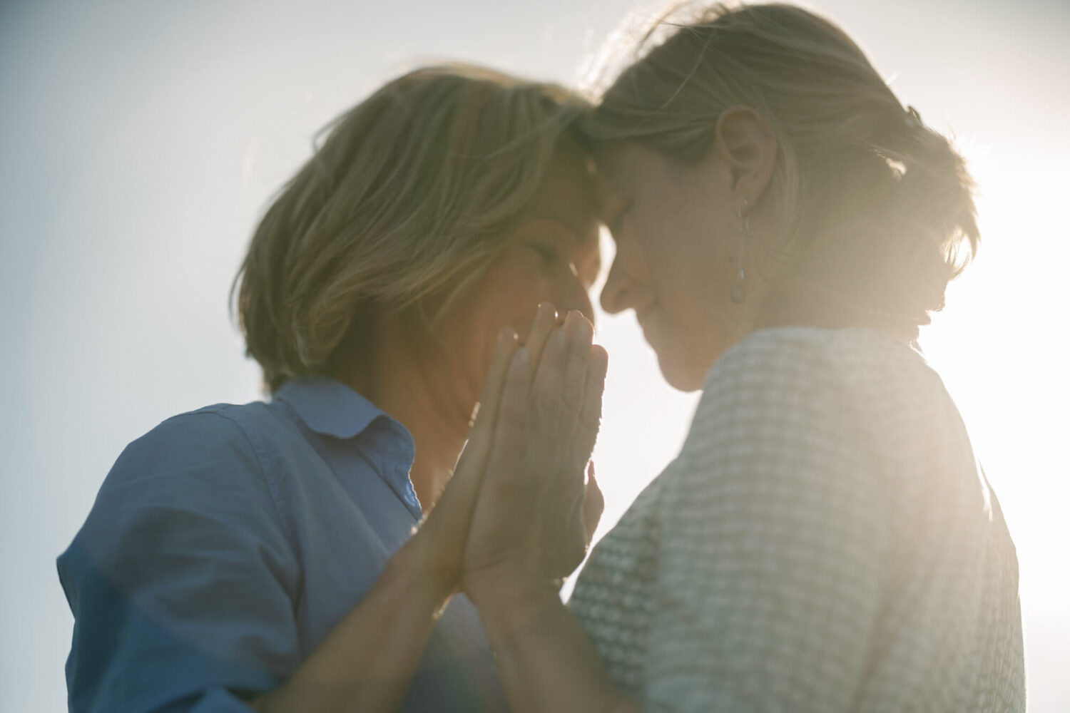 two women hands up palms facing heads together
