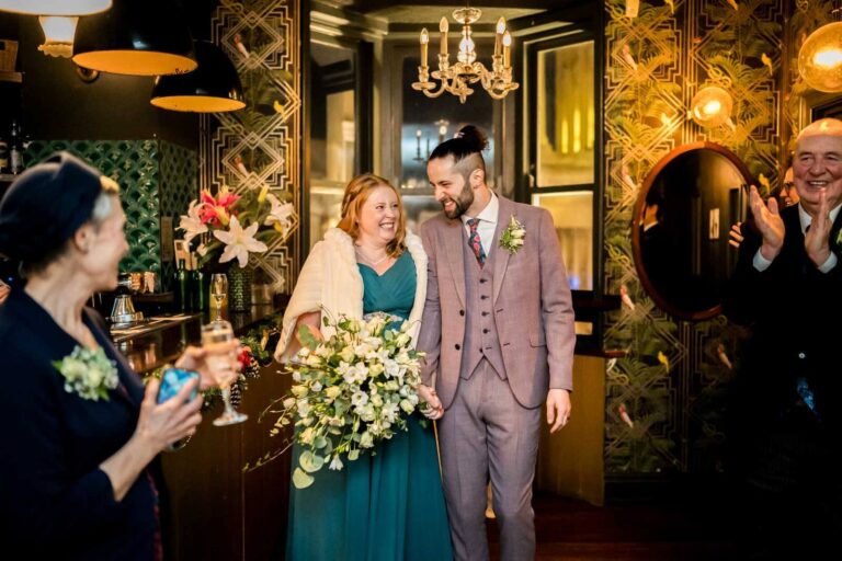 happy couple walk into reception smiling and holding hands