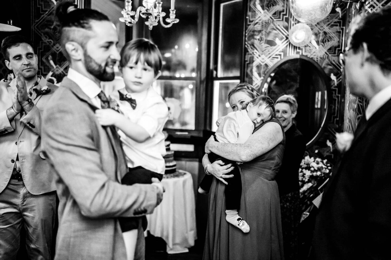 groom giving speech holding his kid and wife and other kid in backgroun