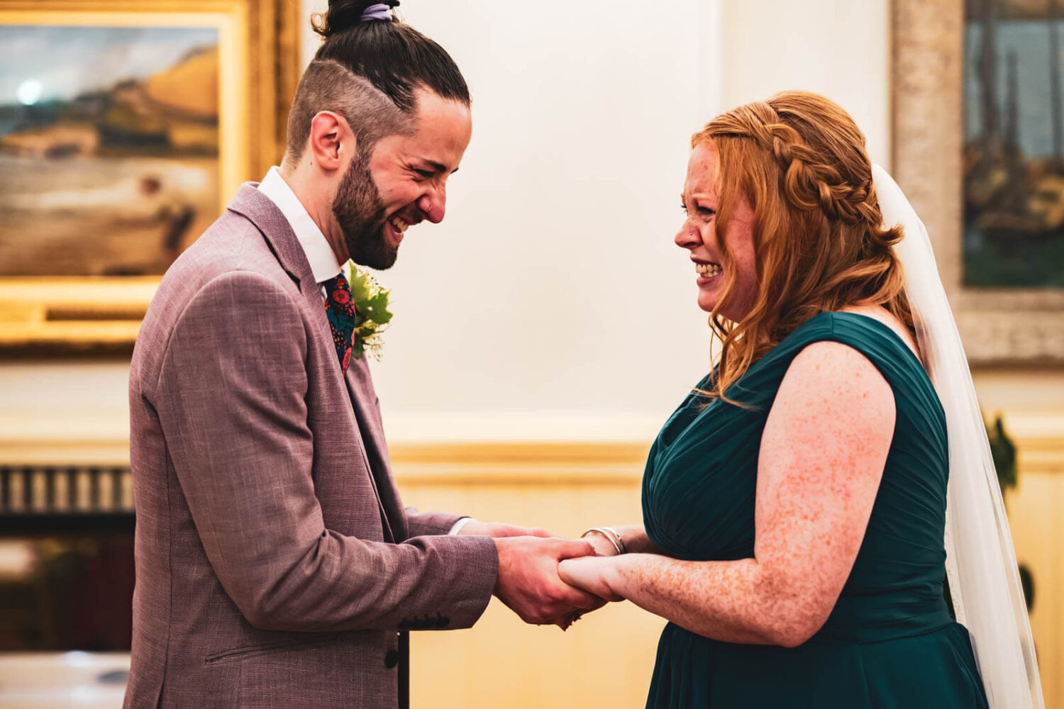 bride and groom holding hands laughing with emotion during ceremony
