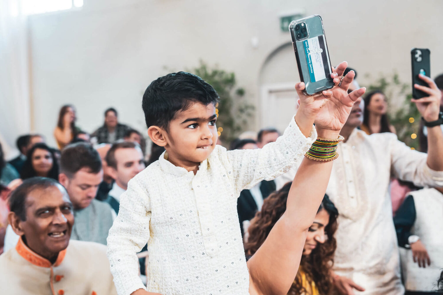 kid holding up phone at hindu ceremony at firle place