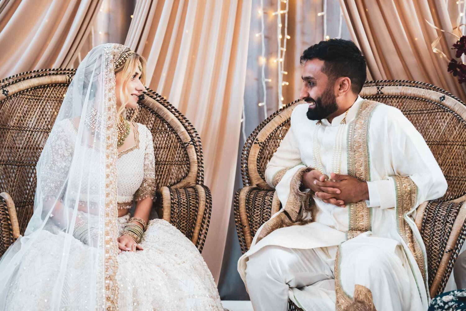 groom and bride smiling at each other at firle place at their mandap
