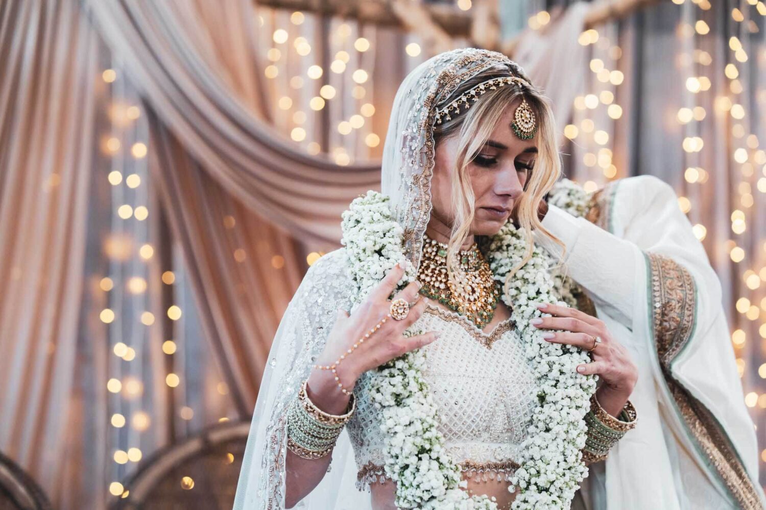 bride holding floral band around her neck at firle place on mandap