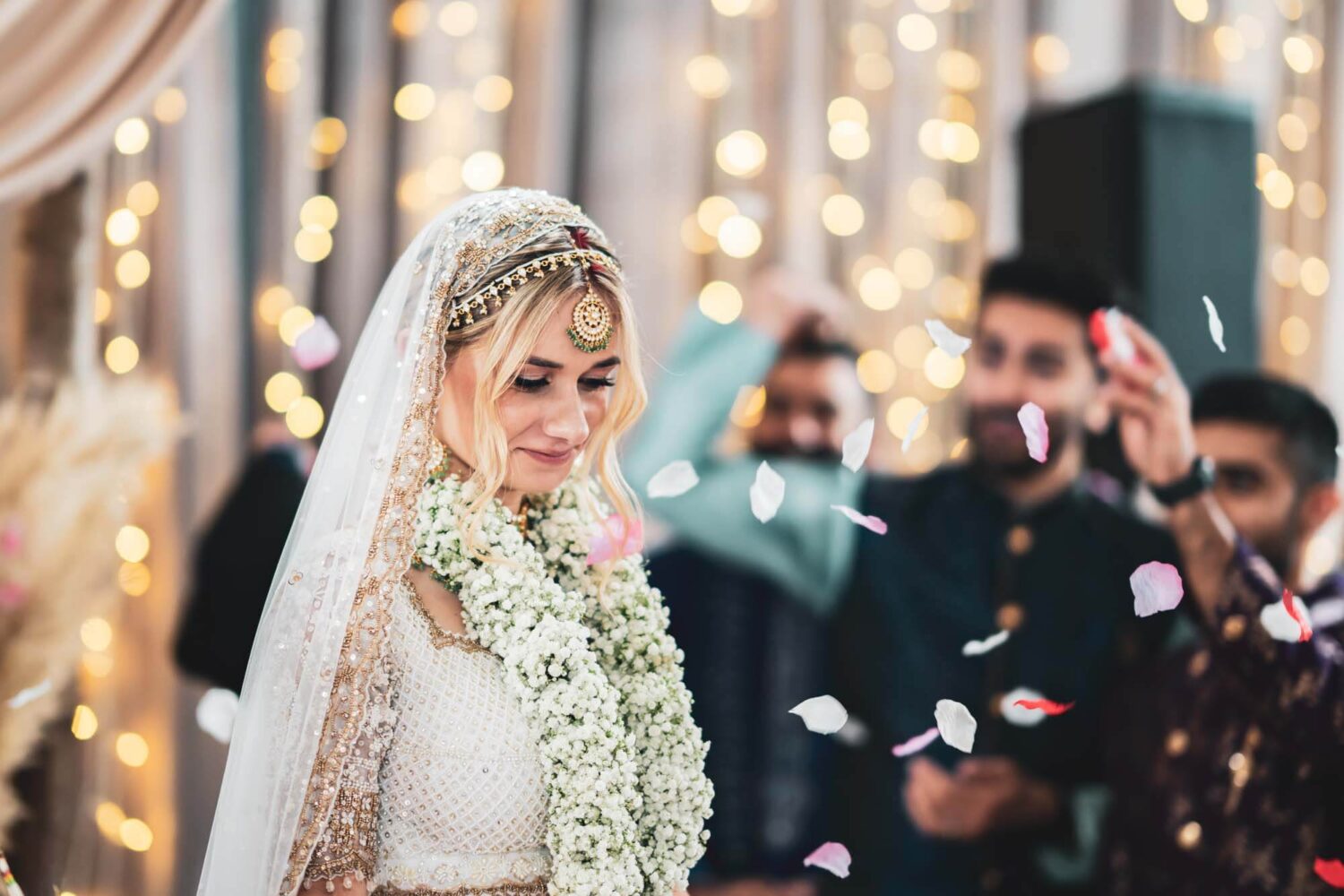 bride having confetti thrown at her on mandap