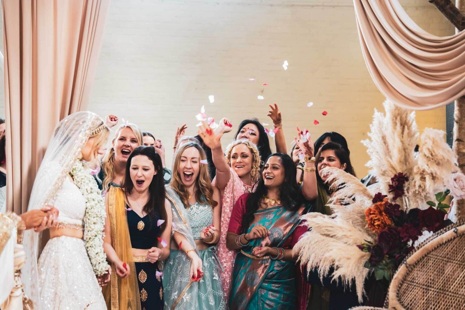 bride having confetti thrown at her on mandap