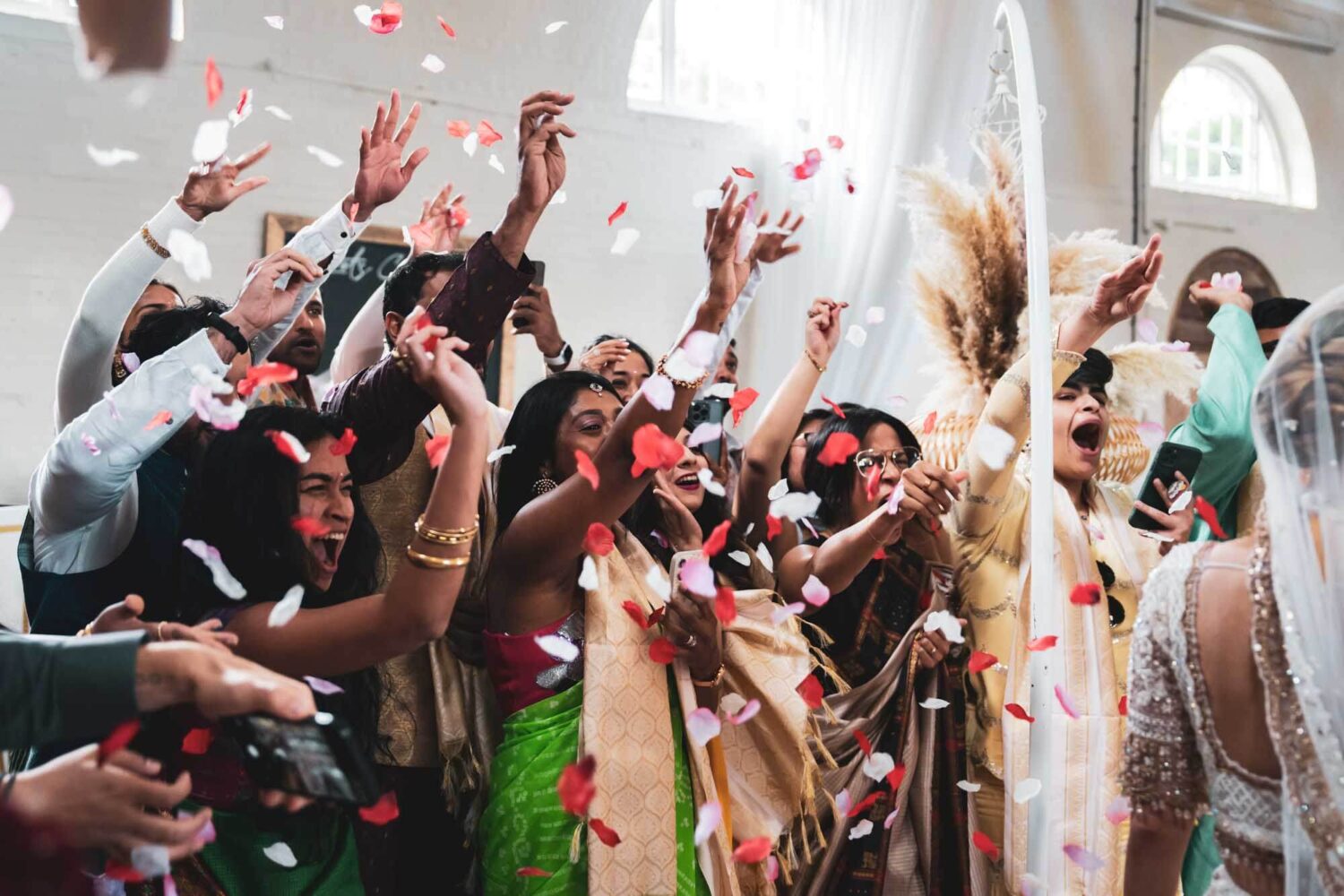 bride having confetti thrown at her on mandap