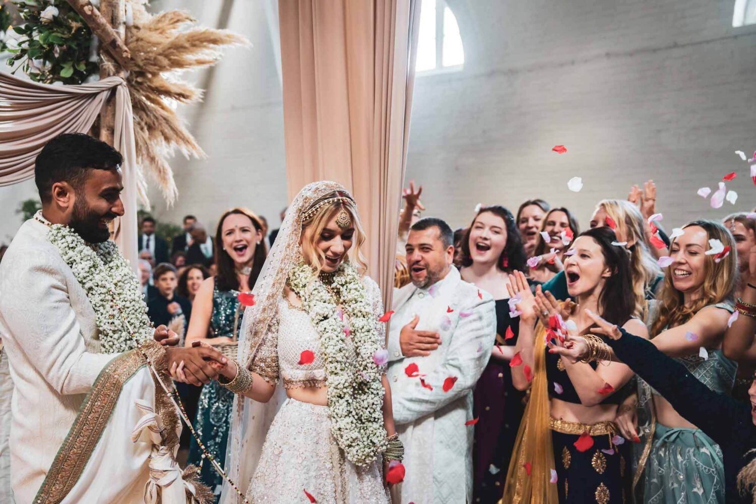 bride having confetti thrown at her on mandap