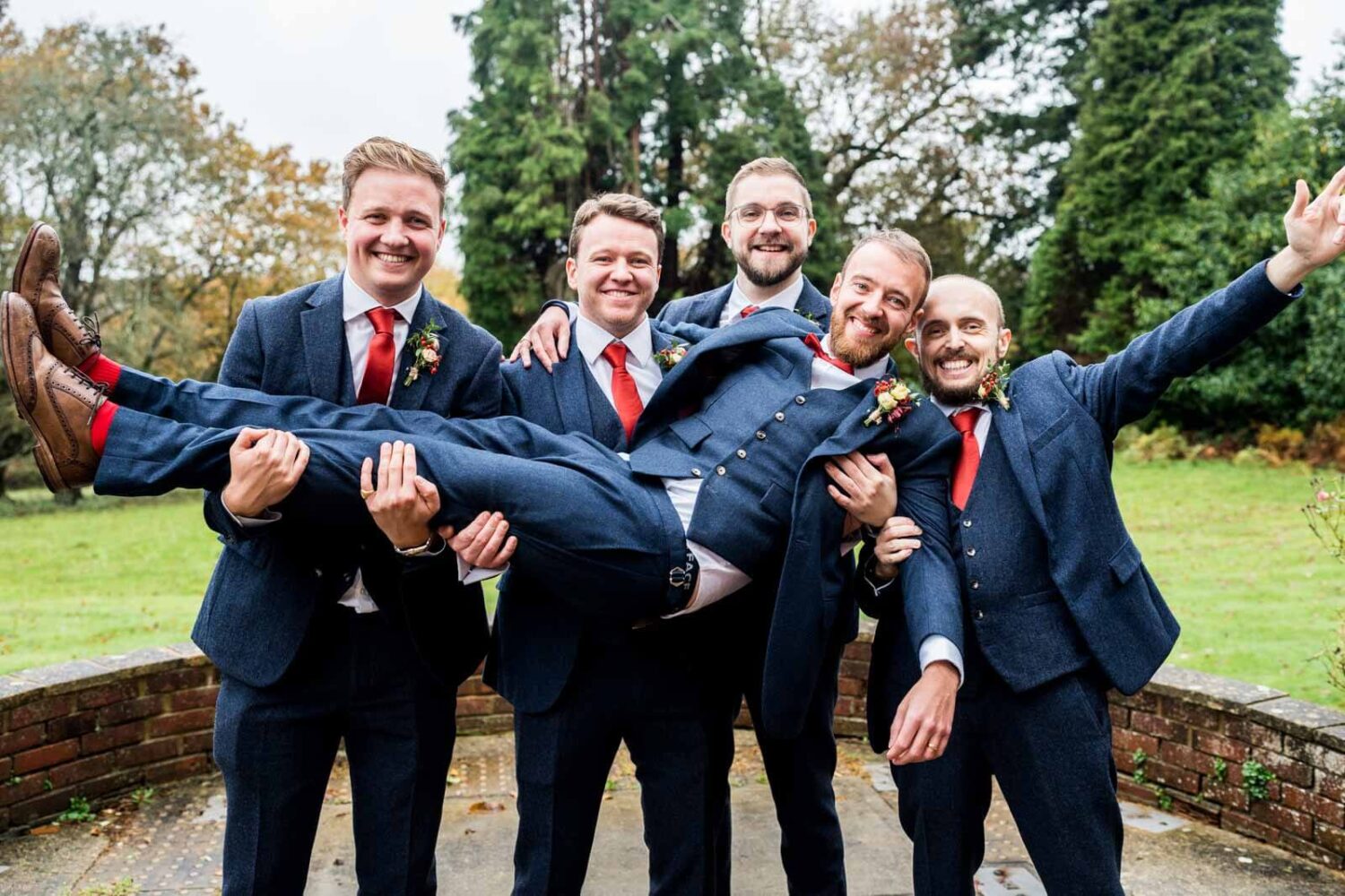 groom being picked up by groomsmen